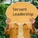 Mand holder orange skilt op med Servant Leadership