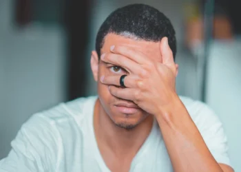 Mand kigger ud gennem fingrene og oplever udbrændthed (udbraendthed)