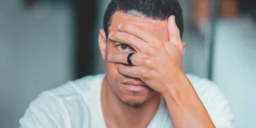 Mand kigger ud gennem fingrene og oplever udbrændthed (udbraendthed)