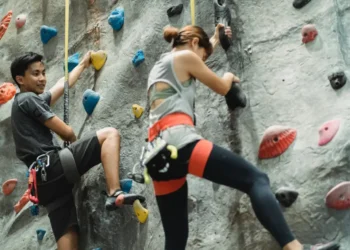 Mand og kvinde hænger på klatrevæg og bruger deres afspadsering her.