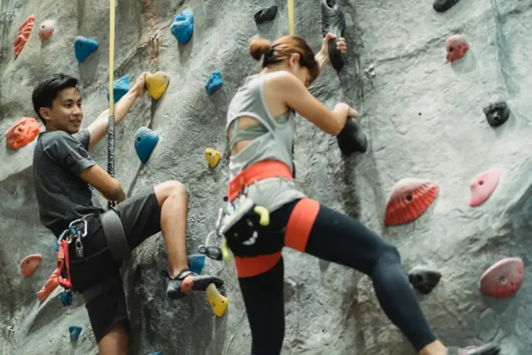 Mand og kvinde hænger på klatrevæg og bruger deres afspadsering her.