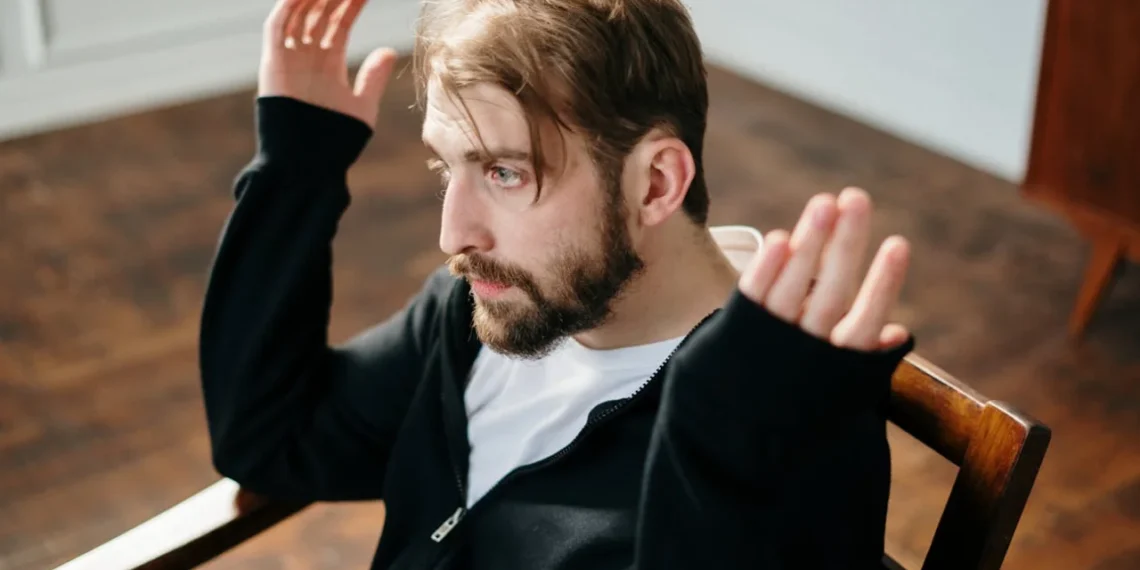 Mand sidder opgivende på stol som i mobning på arbejdspladsen.