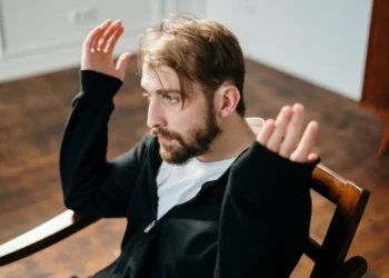 Mand sidder opgivende på stol som i mobning på arbejdspladsen.