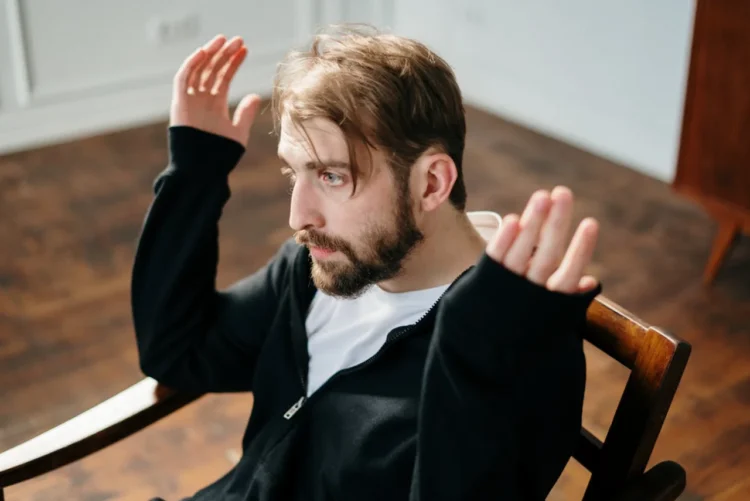 Mand sidder opgivende på stol som i mobning på arbejdspladsen.