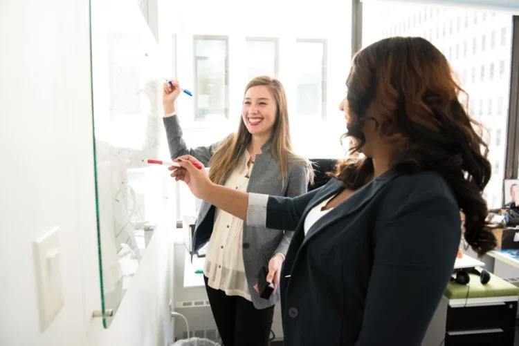 To kvinder ved whiteboard som i engagement.