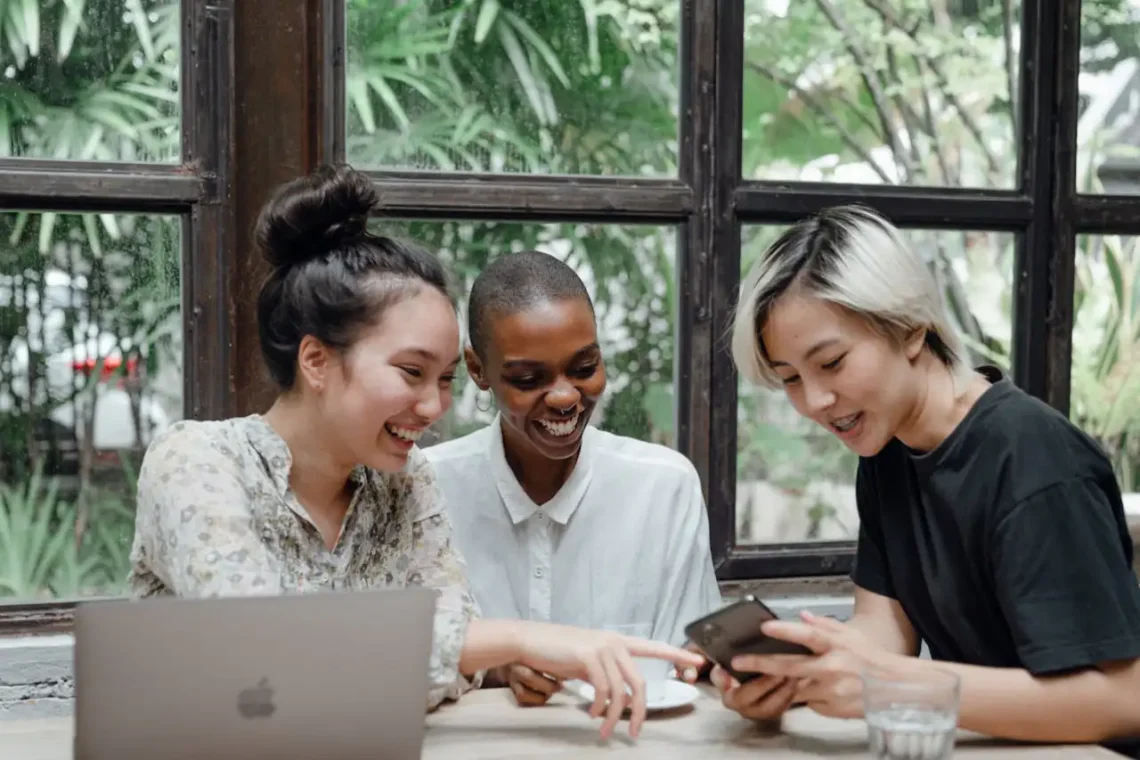 Tre kvinder rundt om en MacBook som i generationsledelse