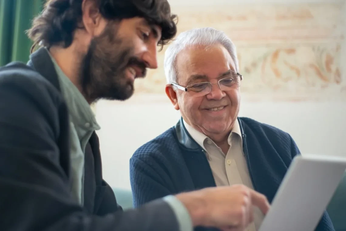 Yngre medarbejder sidder med ældre mentor ved computer.