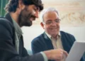 Yngre medarbejder sidder med ældre mentor ved computer.