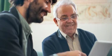 Yngre medarbejder sidder med ældre mentor ved computer.