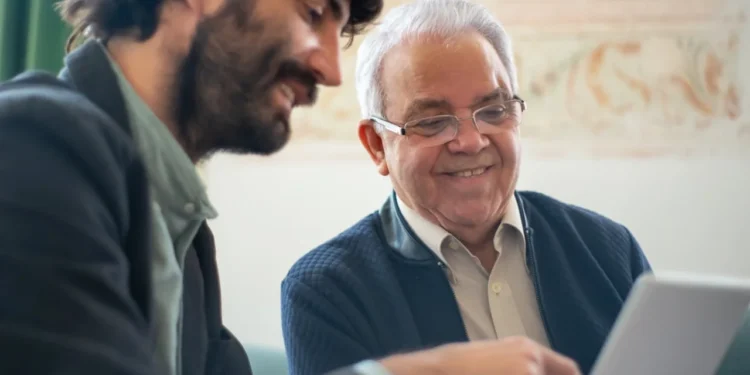 Yngre medarbejder sidder med ældre mentor ved computer.
