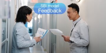 SBI model 2 mennesker i en kontorgang deler feedback med hinanden.