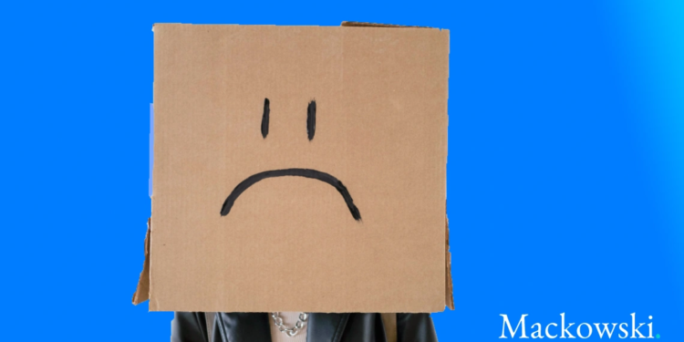 Mistrivsel mand står med papkasse med utilfreds smiley tegnet på kassen